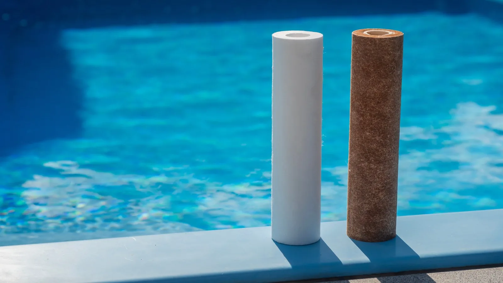A clean water filter cartridge beside a spent one darkened with sediment