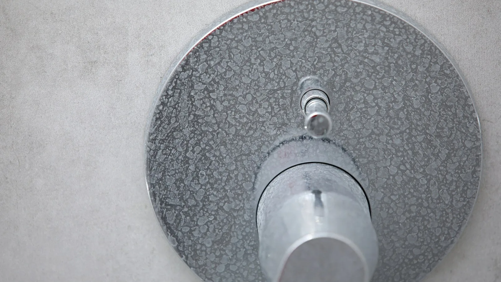 Chrome shower mixer tap coated in white limescale deposits