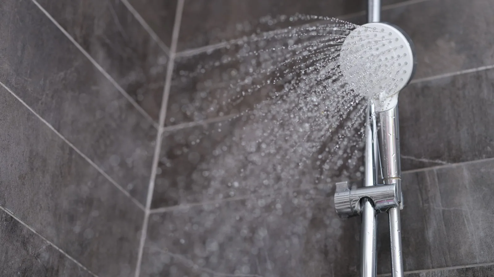 Water running from a chrome shower head in a bright bathroom